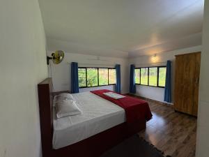 a bedroom with a bed and two windows at FroZen NeST in Vagamon