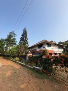 a house with flowers in front of a dirt road at FroZen NeST in Vagamon