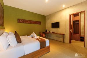 a bedroom with a bed and a desk and a television at ME Villa Pererenan in Canggu
