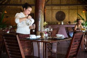 a woman is standing at a table in a restaurant at The Luang Say Lodge in Pakbeng