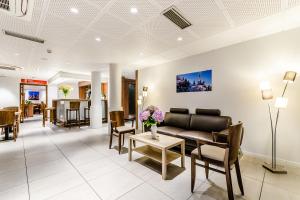 a lobby with a couch and a table and chairs at Hôtel Arcades in Lourdes