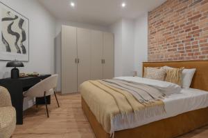 a bedroom with a brick wall and a bed and a desk at HARBOR APARTMENTS - Mickiewicza in Katowice