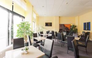 - une salle à manger avec des tables, des chaises et des fenêtres dans l'établissement Hotel Sedes, à Berlin