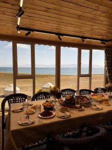 a table with plates of food on the beach at Son-Kul A-Frame & Yurt Camp in Song-Kul