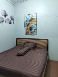 a bed in a room with a painting on the wall at Villa Bukit Asri Berastagi 08 in Berastagi +3 photos