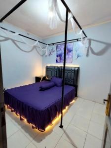 a bedroom with a bed with purple sheets and lights at Villa Bukit Asri Berastagi 08 in Berastagi