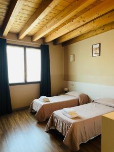 two beds in a room with wooden ceilings and windows at Locanda Munerato in Padova