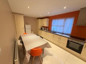 a kitchen with a table with orange chairs and a table and a kitchen with at The Colony Townhouse Dingle in Dingle