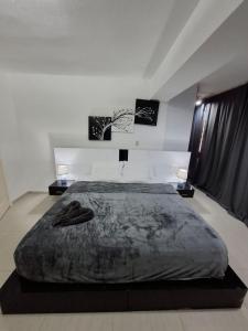 a large bed in a white room with two tables at Ocean View Two Bedroom in Porlamar