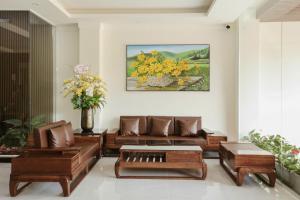 a living room with brown leather furniture and a painting at Hoa Dã Quỳ Hotel in Pleiku