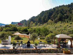a patio with tables and umbrellas in front of a hill at NAIYI Forest Park Resort in Zhangjiajie