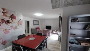 a living room with a red table and a dining room at El Encanto de Valladolid in Aldeamayor de San Martín
