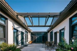 an indoor patio with tables and chairs and windows at LeD Courtyard Homest ay乐东小院民宿 in Beijing