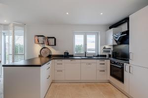 a kitchen with white cabinets and a black counter top at Pure Tinnum in Sylt