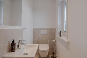 a white bathroom with a toilet and a sink at Pure Tinnum in Sylt +8 photos