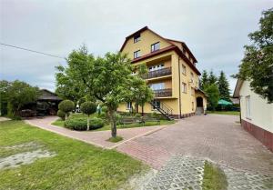 a yellow building with a tree in front of it at Noclegi Michaś in Krasnobród
