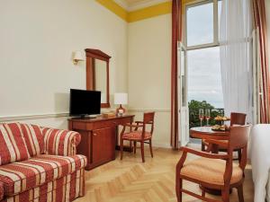 a living room with a couch and a desk with a television at Hotel Continental in Opatija