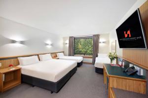 a hotel room with two beds and a flat screen tv at Swiss-Belresort Coronet Peak in Queenstown