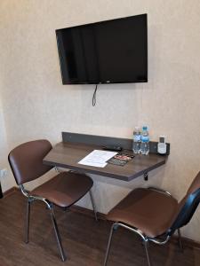 a table with two chairs and a television on a wall at BavariaHotel in Kharkiv
