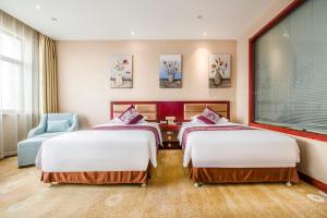 ein Hotelzimmer mit zwei Betten und einem Stuhl in der Unterkunft Minghua Hotel in Wen-su-lao-ch'eng