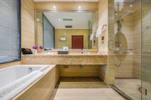 ein Badezimmer mit Badewanne, Dusche und Spiegel in der Unterkunft Minghua Hotel in Wen-su-lao-ch'eng