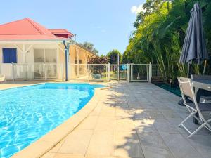 a swimming pool with an umbrella next to a house at BluePalm case in Petit-Bourg