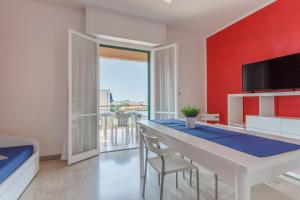 a dining room with a white table and a red wall at Residence Mizar 2 in Pietra Ligure