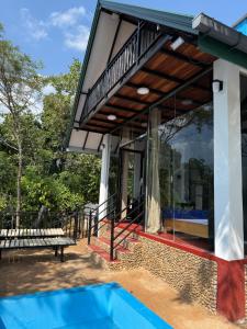 a house with a balcony and a bench in front at Bliss Lodge Diyaluma in Demodara