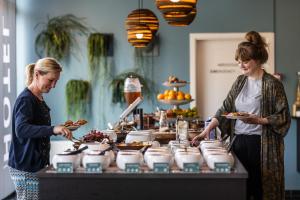 two women standing in front of a buffet with food at Hotel Kolding in Kolding