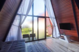 a living room with a large window and a tv at Dieng Ceria Resort in Diyeng