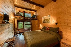a bedroom in a log cabin with a bed and a tv at PinusVillas Private Jacuzzi & Phyto-Sauna in Zheleznitsa