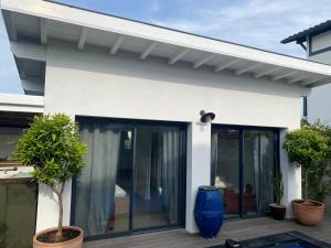 a white house with glass doors and plants at Maison d'architecte 4 chambres avec piscine in Anglet