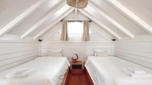 two beds in a attic room with a window at Bacana Bungalows in Uluwatu