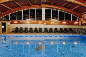 a large swimming pool with chairs in a building at Fried Kastély Hotel Simontornya in Simontornya