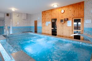 a large swimming pool with blue water in a room at Fried Kastély Hotel Simontornya in Simontornya