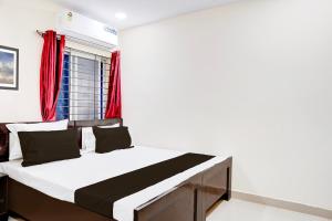 a bed in a room with a red window at Hotel O Shivay Inn Ayodhaya Bypass Road in Bhopal