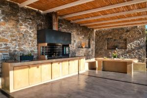 a kitchen with wooden cabinets and a stone wall at Thea Villas in Makry Gialos