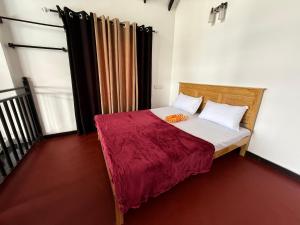 a small bedroom with a bed with a red blanket at Bliss Lodge Diyaluma in Demodara