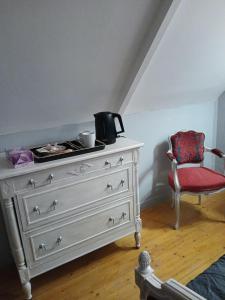 a bedroom with a dresser and a red chair at au calme a 2pas des côtes du finistere sud in Bannalec