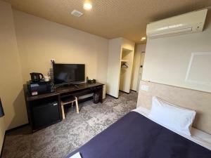 a hotel room with a bed and a flat screen tv at HOTEL LiVEMAX Himeji Ekimae in Himeji