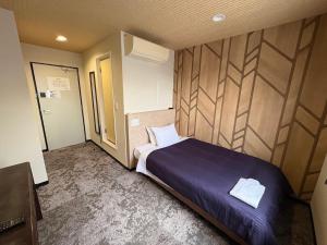 a bedroom with a large bed and a wooden wall at HOTEL LiVEMAX Himeji Ekimae in Himeji