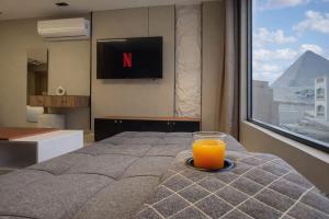 a glass of orange juice sitting on a bed with a window at Pyramids Height Luxury Wing in Cairo