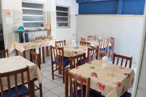a dining room with tables and chairs and a kitchen at Hotel Paulista in São Vicente