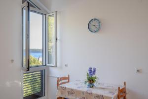 a dining room with a table and a clock on the wall at Apartments Lea in Prizba