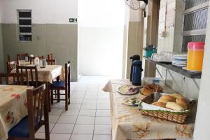a kitchen with two tables and a table with bread at Hotel Paulista in São Vicente