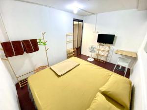 a bedroom with a yellow bed and a tv at J&T House And Friends in Ban Khlong Nam Ron
