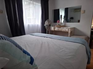 a bedroom with a bed with a mirror and a table at Melrose Garden Cottages - Hibiscus Cottage in Durban