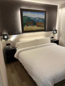 a bedroom with a white bed and a painting on the wall at Hotel Guineu in Pas de la Casa +40 photos