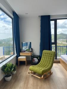 a living room with a green chair and large windows at HOTEL vùng vịnh in Cầu Sông Kinh