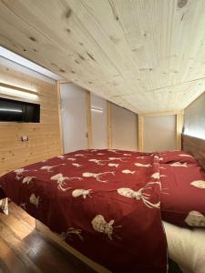 a bedroom with a bed with a red comforter at Lilli apartment in Aprica